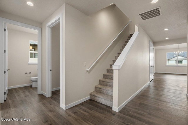 stairway featuring visible vents, wood finished floors, recessed lighting, an inviting chandelier, and baseboards