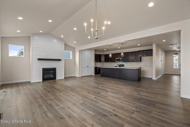 unfurnished living room with dark wood finished floors, lofted ceiling, baseboards, and a large fireplace