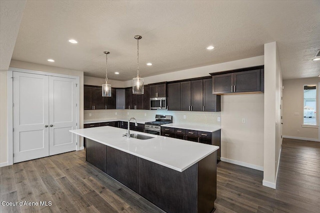 kitchen with dark wood finished floors, decorative backsplash, stainless steel appliances, and a sink