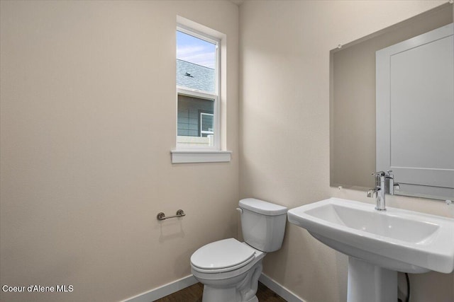 bathroom featuring wood finished floors, toilet, baseboards, and a sink