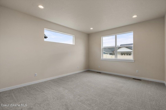 empty room featuring carpet flooring, a healthy amount of sunlight, and visible vents