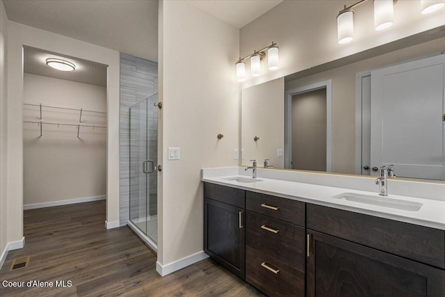 bathroom with wood finished floors, a stall shower, and a sink