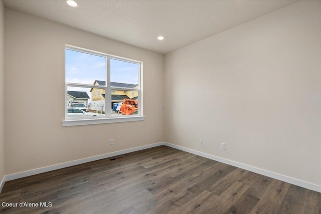 spare room featuring visible vents, a textured ceiling, wood finished floors, recessed lighting, and baseboards