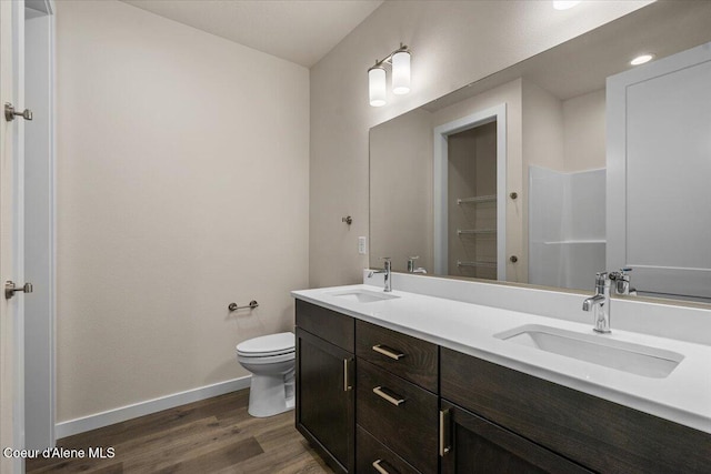 bathroom with a sink, baseboards, toilet, and wood finished floors