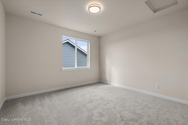 carpeted spare room with visible vents, baseboards, and a textured ceiling