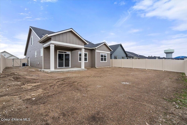 back of house with a fenced backyard, board and batten siding, a patio, and a gate