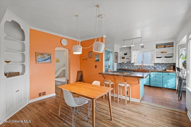 dining area featuring visible vents, wood finished floors, arched walkways, crown molding, and baseboards