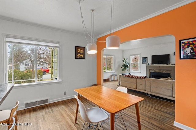 dining area with crown molding, wood finished floors, visible vents, and baseboards