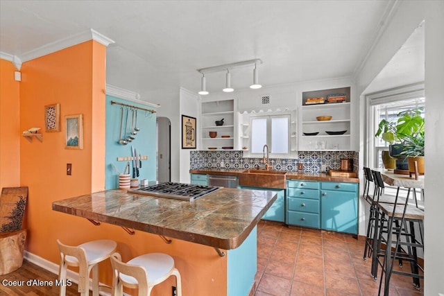 kitchen with open shelves, arched walkways, a sink, appliances with stainless steel finishes, and dark countertops