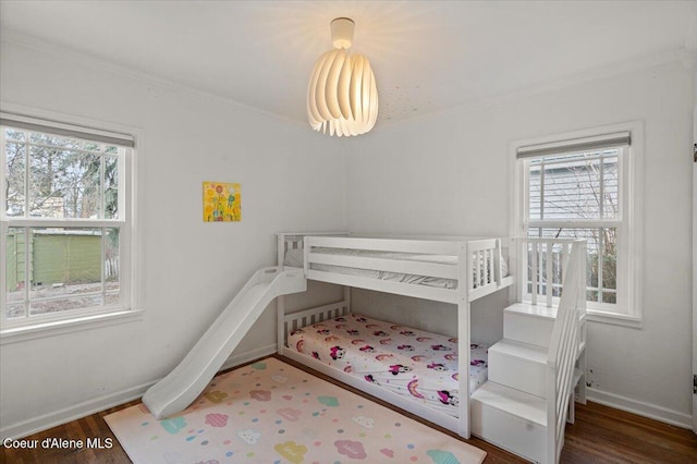 bedroom featuring baseboards, multiple windows, and wood finished floors