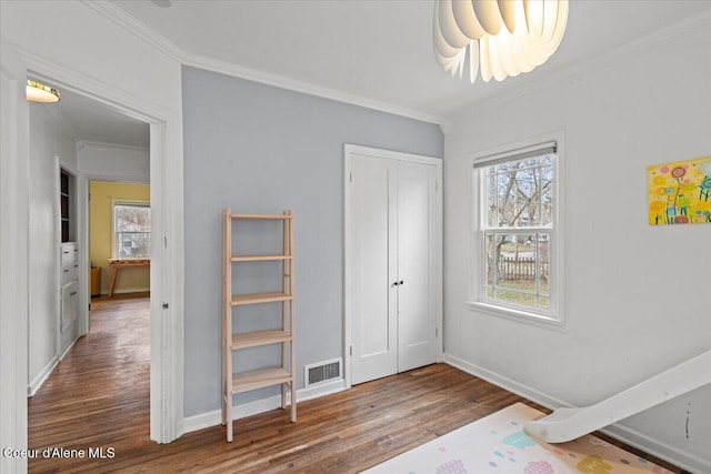 bedroom featuring crown molding, multiple windows, wood finished floors, and visible vents