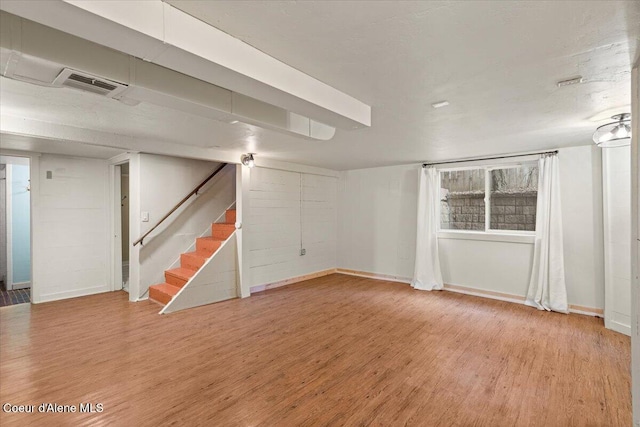 finished below grade area with stairs, baseboards, visible vents, and light wood finished floors