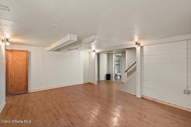 interior space featuring a textured ceiling, stairs, baseboards, and wood finished floors