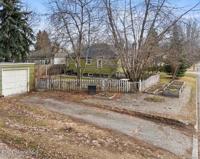 view of yard with an outbuilding, fence, driveway, a garden, and a garage