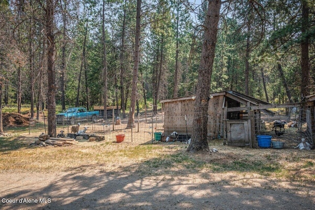 view of yard with an outbuilding, a view of trees, and exterior structure