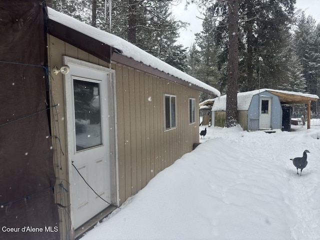 view of snowy exterior with an outbuilding and a storage unit