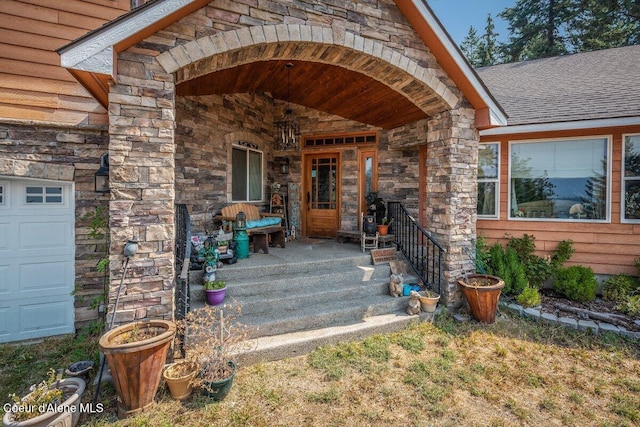 entrance to property with a garage, stone siding, covered porch, and a shingled roof