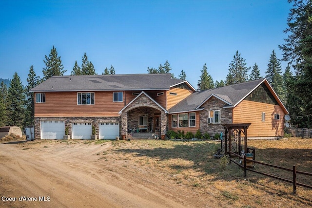 view of front of property with an attached garage, fence, stone siding, and driveway