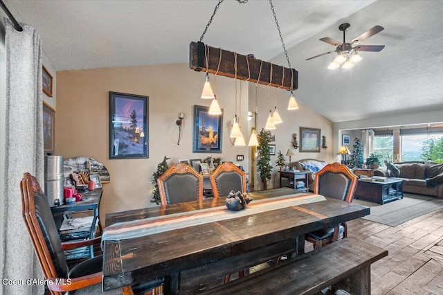 dining room with ceiling fan, a textured ceiling, wood finished floors, and vaulted ceiling