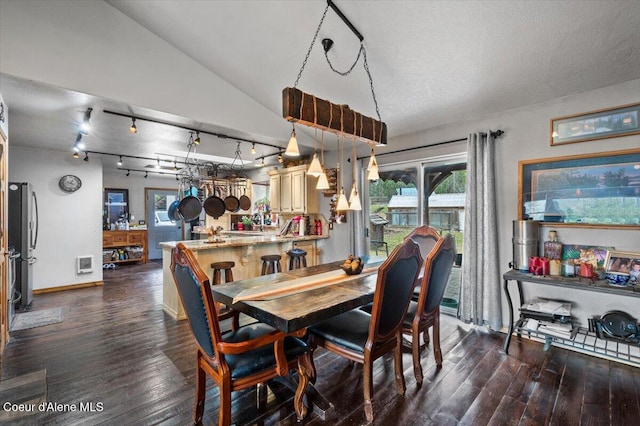 dining room featuring dark wood-style floors, a textured ceiling, baseboards, and lofted ceiling