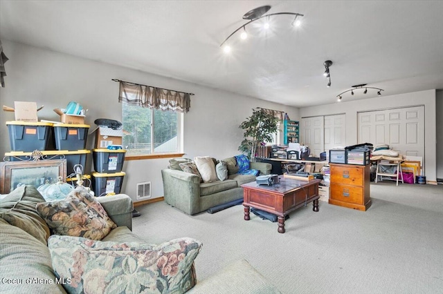 carpeted living area with visible vents, baseboards, and rail lighting