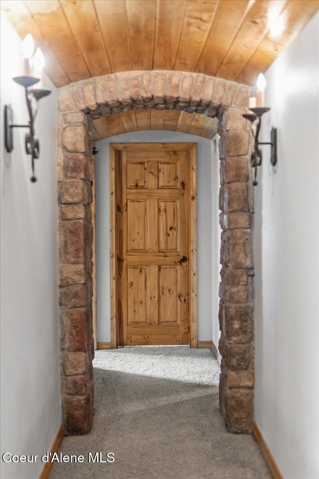 corridor featuring baseboards, wooden ceiling, and carpet flooring