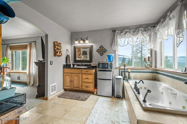 bathroom with tile patterned floors, visible vents, vanity, and a whirlpool tub