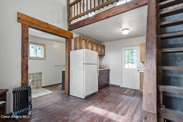 kitchen with dark wood finished floors, light countertops, baseboards, and freestanding refrigerator