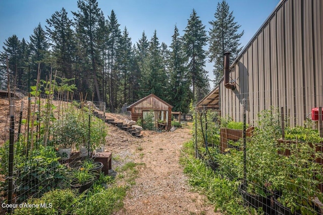 view of yard featuring fence, an outdoor structure, and a garden