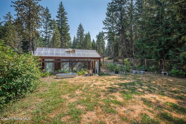 view of yard with an exterior structure, a view of trees, an outdoor structure, and fence