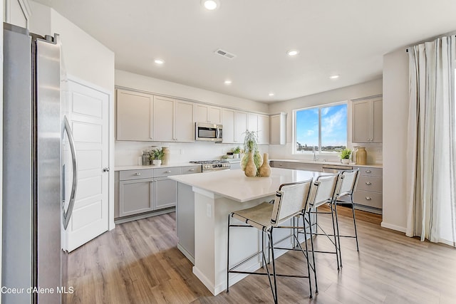 355 E Burdock Loop, Hayden, ID 83835 - kitchen featuring visible vents, gray cabinetry, a center island, a breakfast bar area, and stainless steel appliances