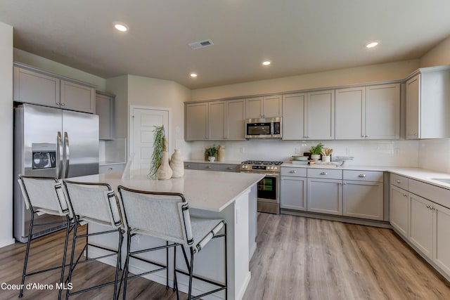 355 E Burdock Loop, Hayden, ID 83835 - kitchen with a kitchen bar, appliances with stainless steel finishes, light wood-style flooring, and gray cabinetry