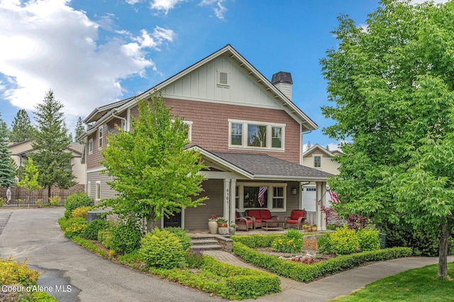 view of front of house featuring covered porch, a chimney, and fence