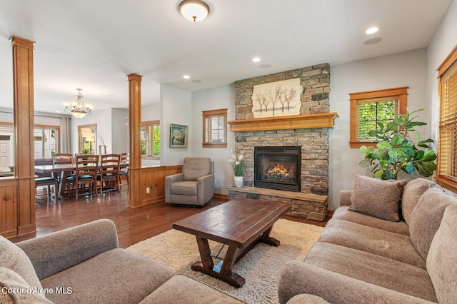 living area with a stone fireplace, plenty of natural light, ornate columns, and wood finished floors