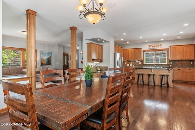 dining space featuring recessed lighting, an inviting chandelier, ornate columns, and dark wood-style flooring