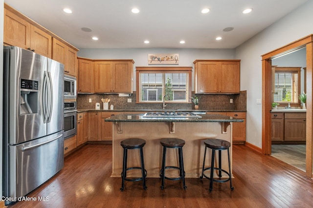 kitchen with tasteful backsplash, dark wood-style flooring, appliances with stainless steel finishes, and a kitchen island