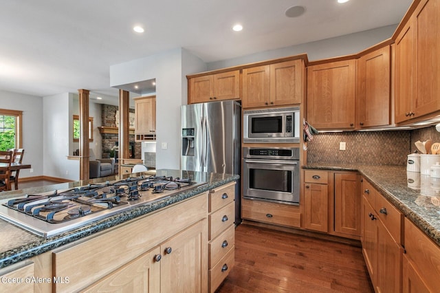 kitchen featuring dark wood finished floors, dark stone counters, recessed lighting, stainless steel appliances, and decorative backsplash