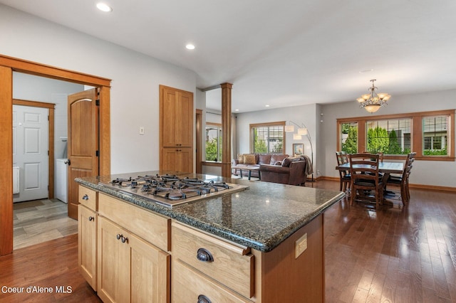 kitchen with dark wood-style floors, baseboards, a kitchen island, an inviting chandelier, and stainless steel gas stovetop