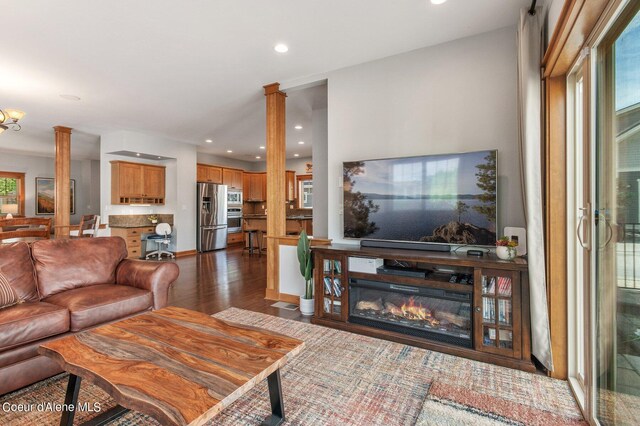 living area featuring recessed lighting, baseboards, dark wood-type flooring, and ornate columns