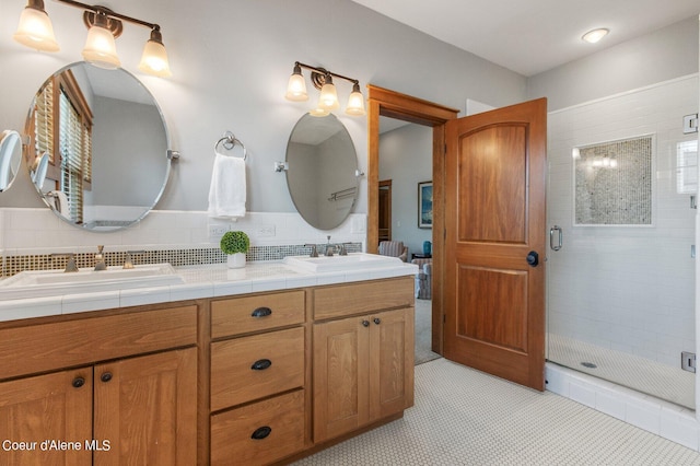 bathroom featuring double vanity, decorative backsplash, a stall shower, and a sink