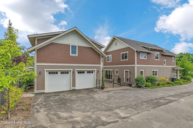 view of front facade featuring central air condition unit, driveway, board and batten siding, and an attached garage