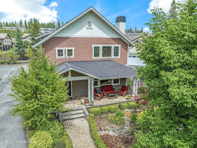 view of front of house with board and batten siding, a chimney, and a patio