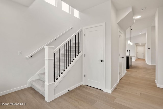 stairway with wood finished floors, baseboards, and high vaulted ceiling