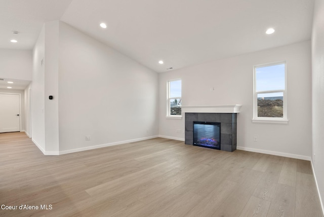 unfurnished living room with a healthy amount of sunlight, a fireplace, light wood-type flooring, and baseboards