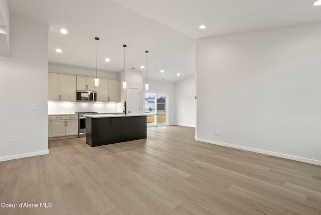 kitchen featuring light wood finished floors, open floor plan, appliances with stainless steel finishes, light countertops, and baseboards