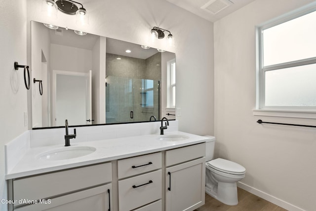 bathroom with a sink, toilet, a stall shower, and double vanity