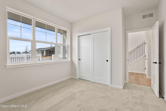 unfurnished bedroom with visible vents, baseboards, carpet, and a closet