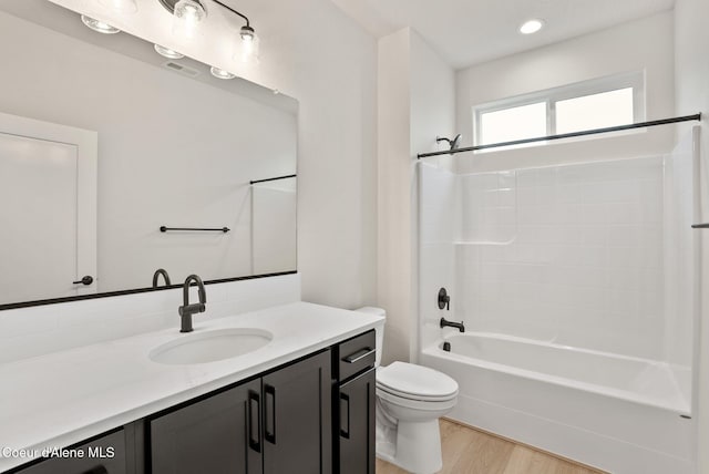 full bathroom with visible vents, toilet, wood finished floors, washtub / shower combination, and vanity