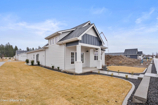 modern farmhouse with a front lawn, board and batten siding, and roof with shingles