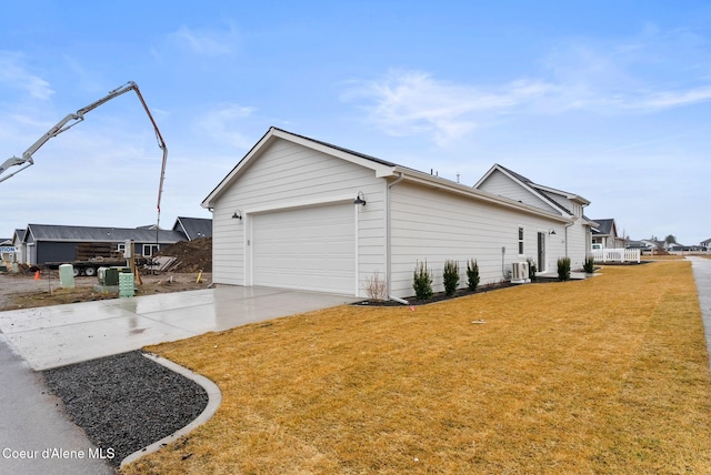 view of home's exterior featuring a yard, an attached garage, central AC, and driveway